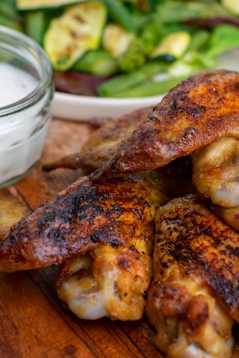 Finished chicken wings with vegetables on a wooden board