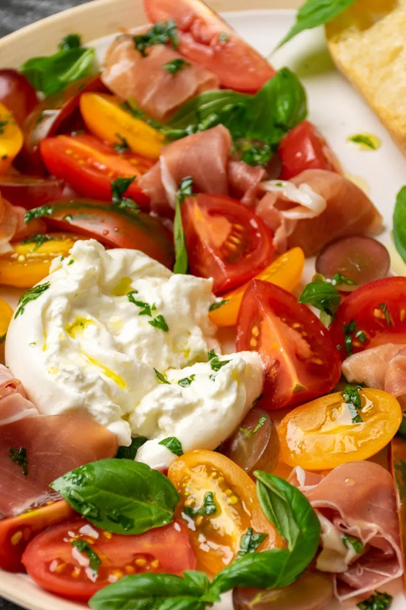 Quick tomato salad with burrata cheese, grapes and prosciutto