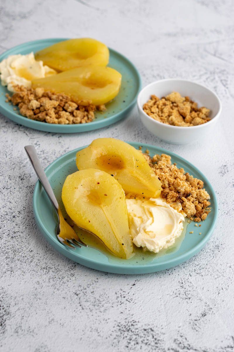 two poached pears on a plate with cream