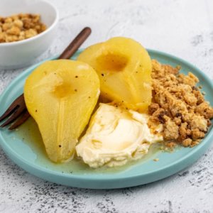 two poached pears on a plate with cream