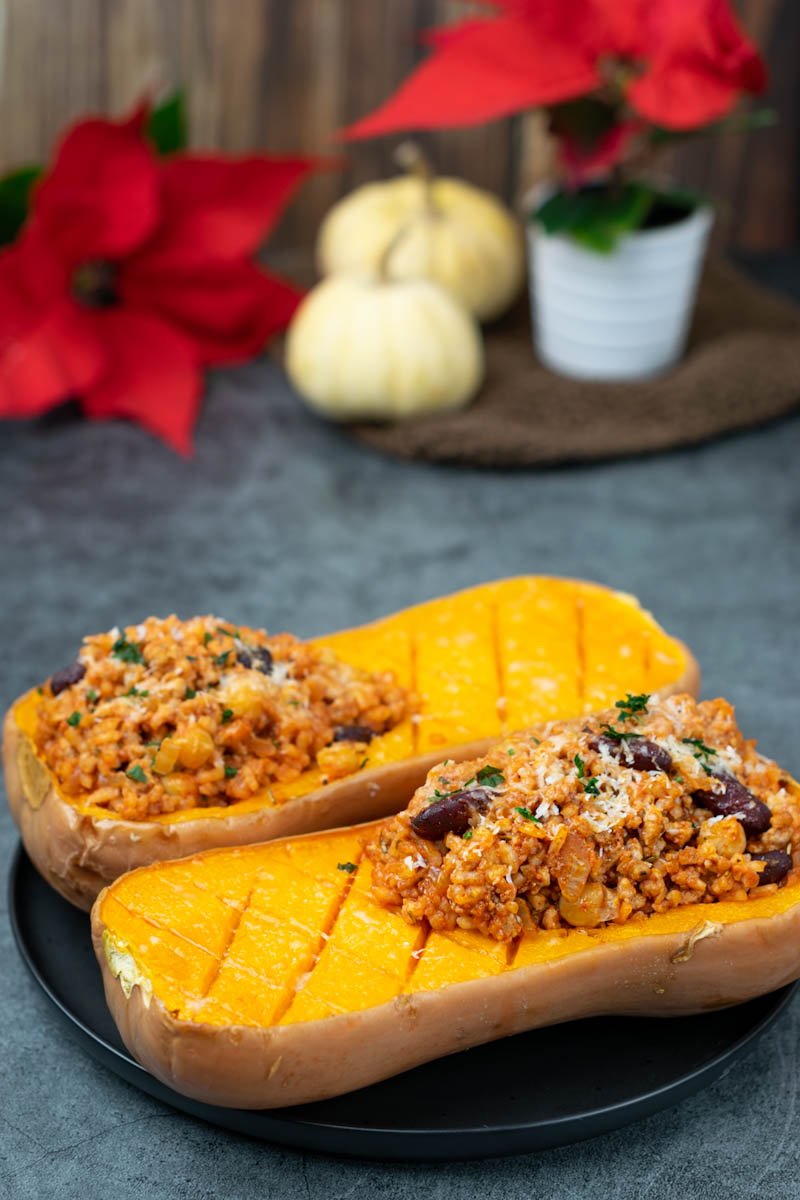 Two stuffed butternut squash on the black plate. 