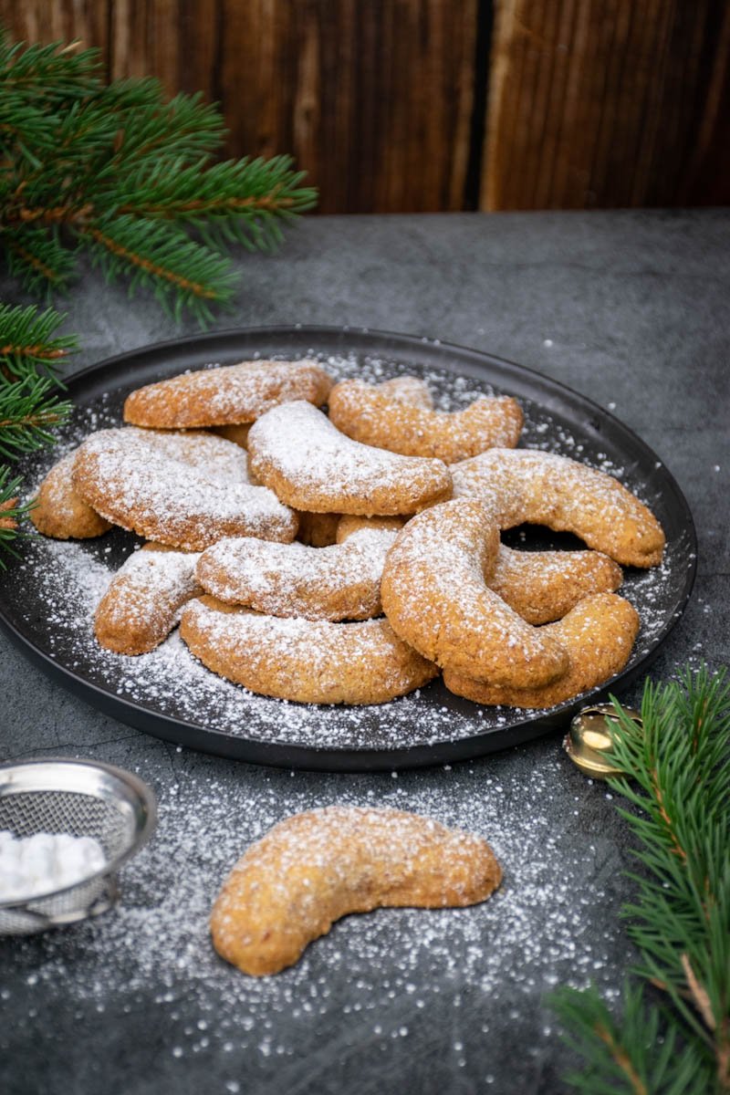 Almond cookies sprinkled with sugar on a black plate. 